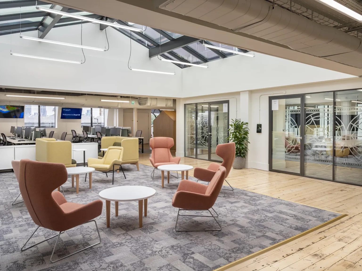Breakout lounge at Dept W, Queen Mary University of London, with soft seating beneath a restored Edwardian rooflight.